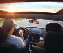 Distracted Driving, man using cell phone while driving car with passenger 