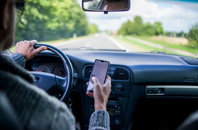 Distracted Driving, man using cell phone while driving car with passenger 