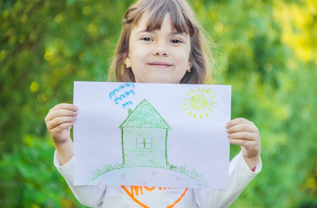 Little girl holding drawing of a green home