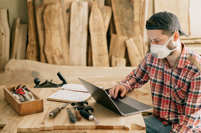 Handyman with mask working on computer