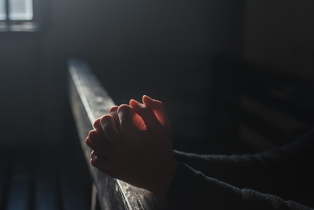 Clasped hands praying on pew